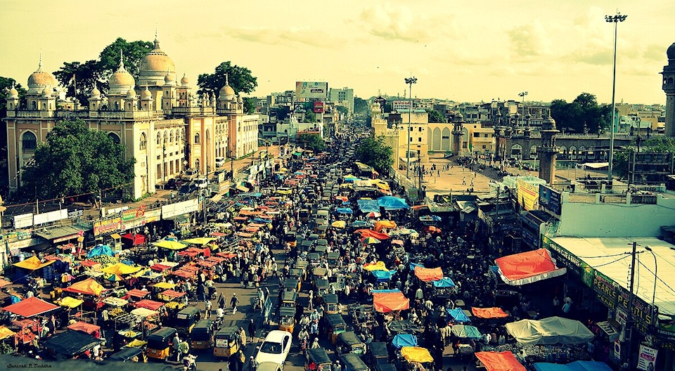Street in a city in India full of traffic, vendors, and pedestrians